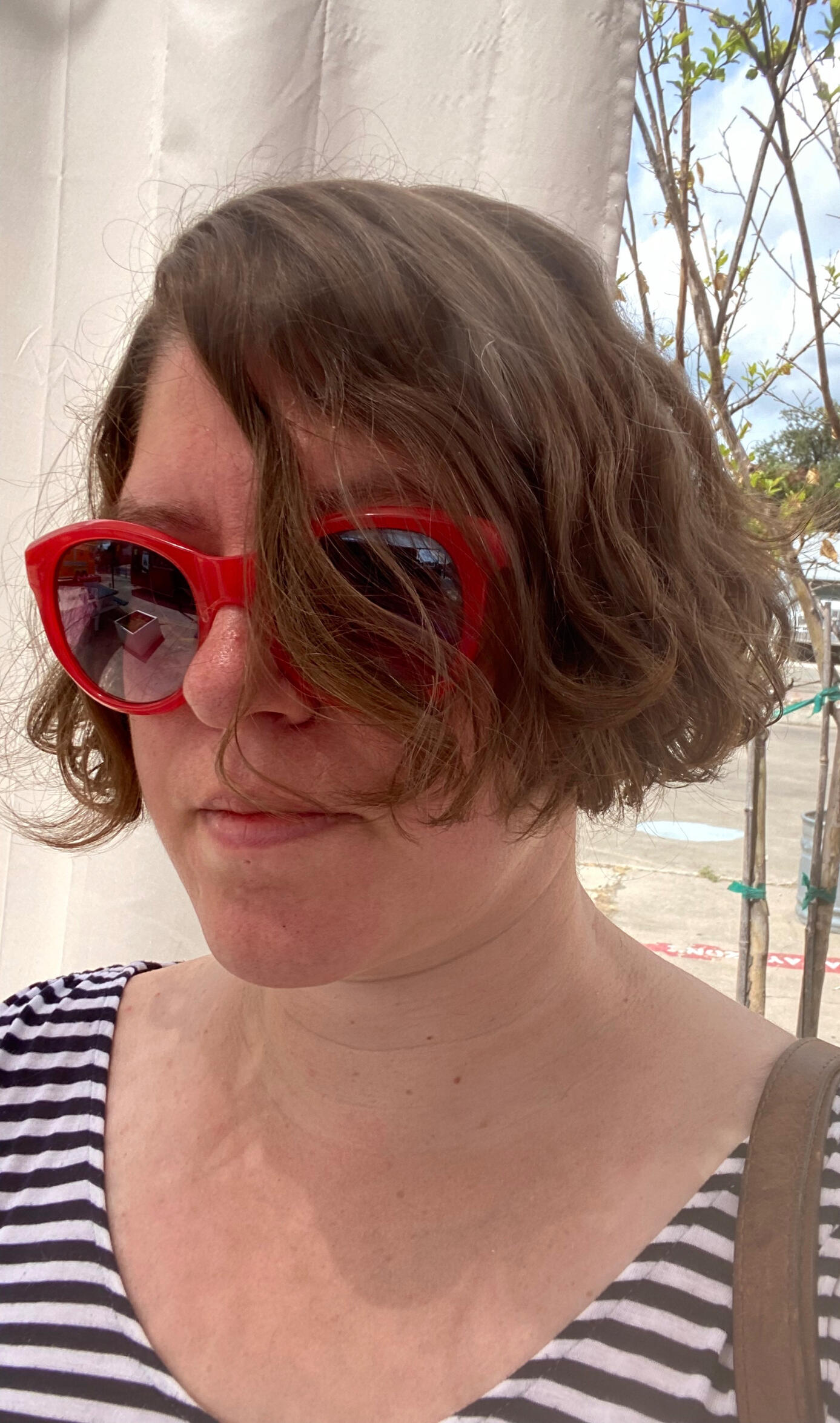 A woman with red sunglasses and a black and white striped top.